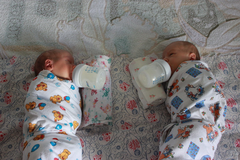 Новорожденные дети дома малютки. Кормление из бутылочки двойни. Новорождённые двойняшки в кроватке. Младенцы Близнецы в кроватке.